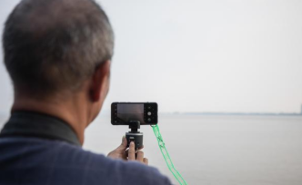 老人拍潮水很拼，將手機綁江邊護欄：現(xiàn)在手機被潮打一下沒事