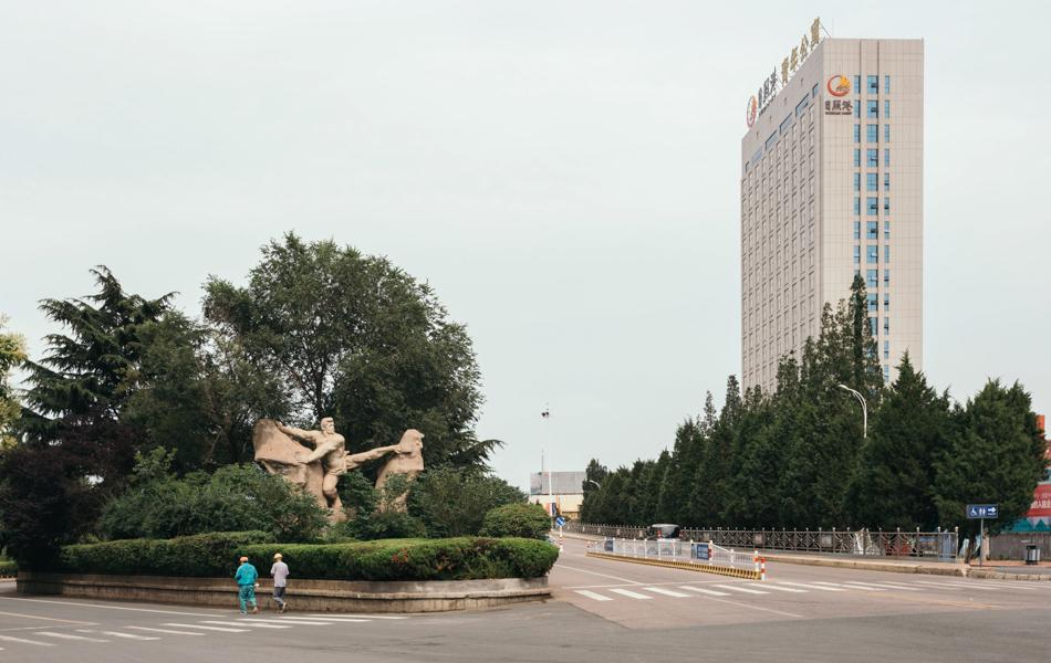 12 大力士  strong man  2016年，通往日照燈塔風(fēng)景區(qū)的路上，遠(yuǎn)處日照港的大樓和一尊寓意不畏艱難的雕像。  拷貝