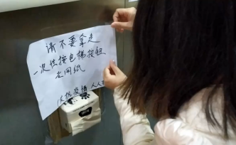 她在電梯內(nèi)粘抽紙，方便鄰居無接觸按電梯