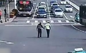 老人马路中央缓慢行走，协警护着过马路