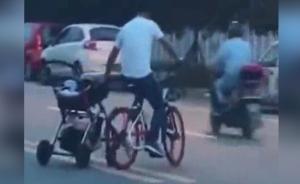 男子边推婴儿车，边骑共享单车横穿马路